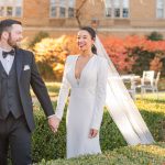 Bride and groom walk in the rose garden in the Fall